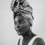 Black and white portrait of a Nigerian woman wearing a patterned headwrap, reflecting African elegance.