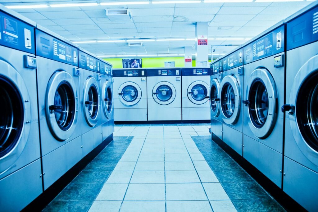 A contemporary laundromat with rows of industrial washing machines and bright interior lighting.